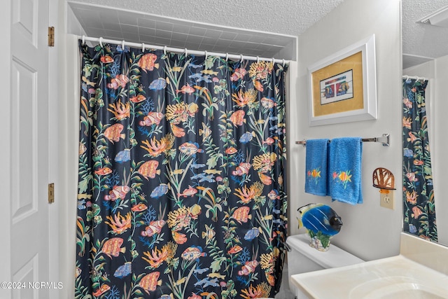 bathroom with vanity, a textured ceiling, toilet, and walk in shower