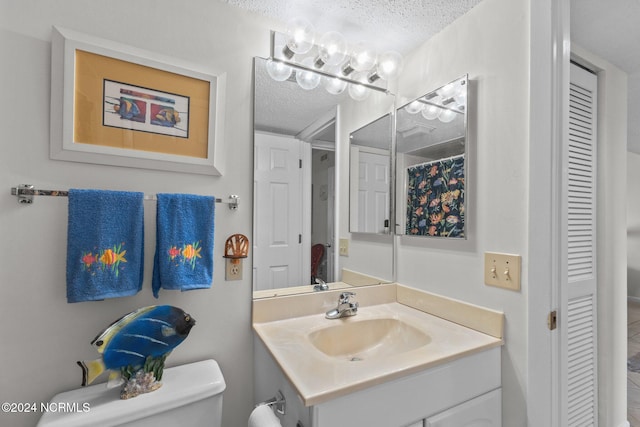 bathroom featuring vanity, a textured ceiling, and toilet