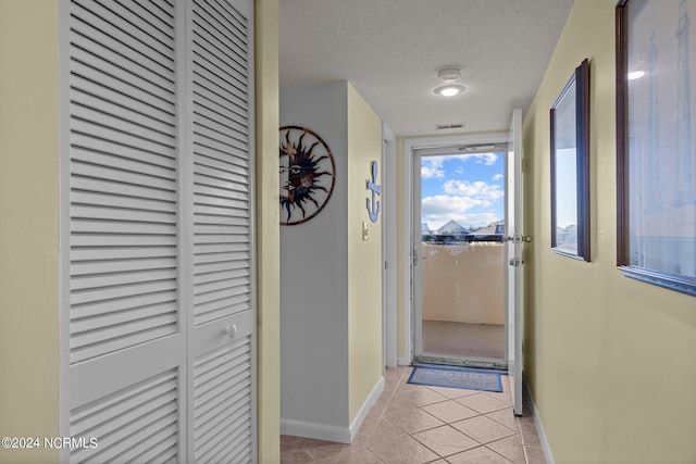 hall with a textured ceiling and light tile patterned floors