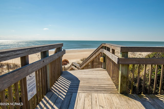 exterior space featuring a deck with water view and a beach view