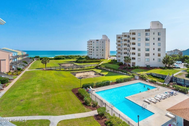 view of pool featuring a patio area, a water view, and a lawn