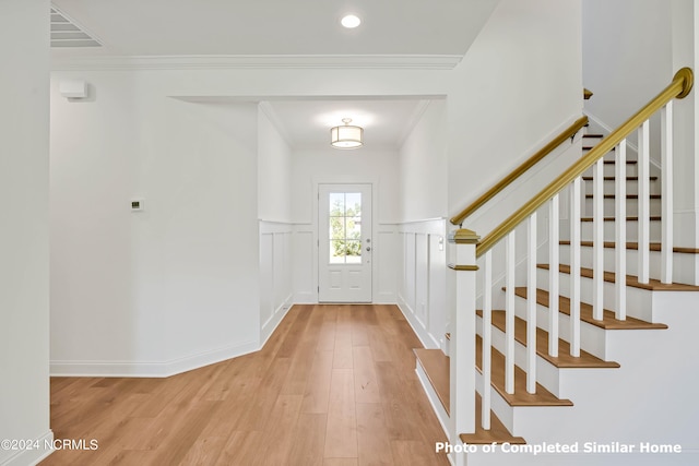 foyer with light hardwood / wood-style floors and ornamental molding