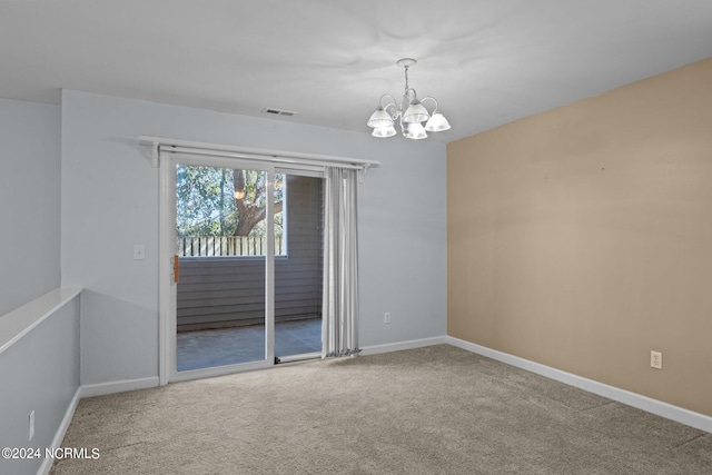 carpeted empty room featuring a chandelier