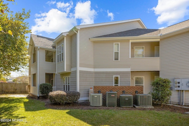 rear view of house featuring a lawn and central AC unit