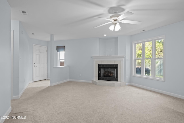 unfurnished living room featuring light colored carpet, a tile fireplace, and ceiling fan