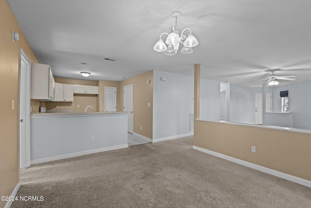 unfurnished living room featuring light carpet, sink, and ceiling fan with notable chandelier