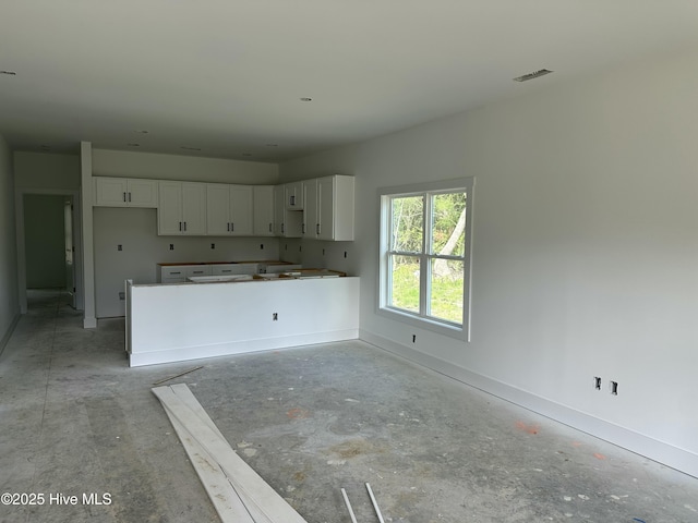 kitchen with baseboards, white cabinets, and visible vents
