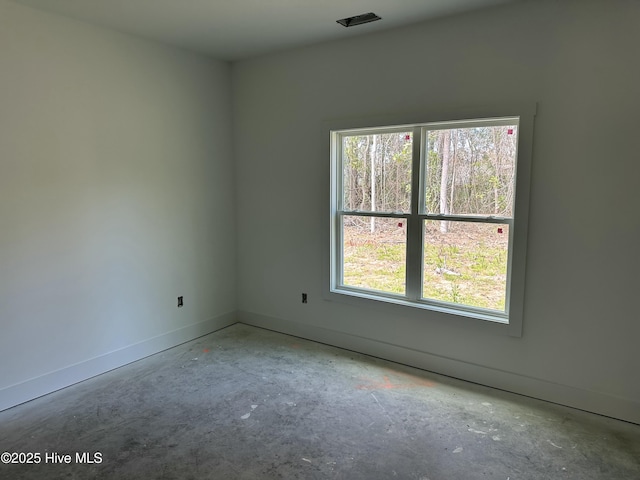 empty room with a wealth of natural light, visible vents, and baseboards