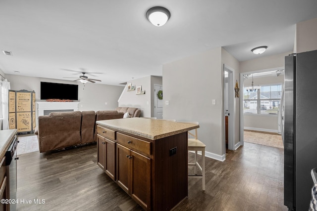 kitchen featuring appliances with stainless steel finishes, a breakfast bar, ceiling fan, dark wood-type flooring, and a center island