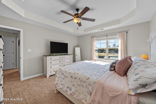 carpeted bedroom featuring a raised ceiling and ceiling fan