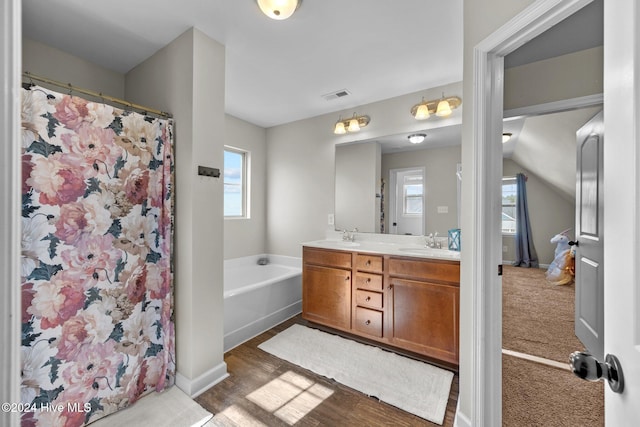 bathroom featuring vanity, wood-type flooring, and a tub to relax in