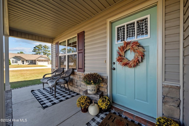 view of exterior entry with a lawn and a porch