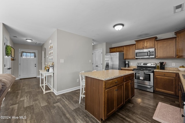 kitchen featuring a breakfast bar, stainless steel appliances, a kitchen island, and dark wood-type flooring