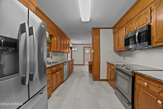 kitchen featuring sink, light stone counters, stainless steel appliances, and backsplash