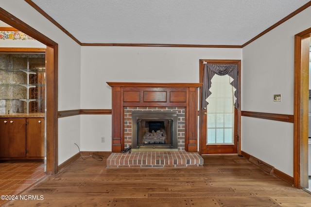 unfurnished living room with ornamental molding, light hardwood / wood-style flooring, a textured ceiling, and a fireplace