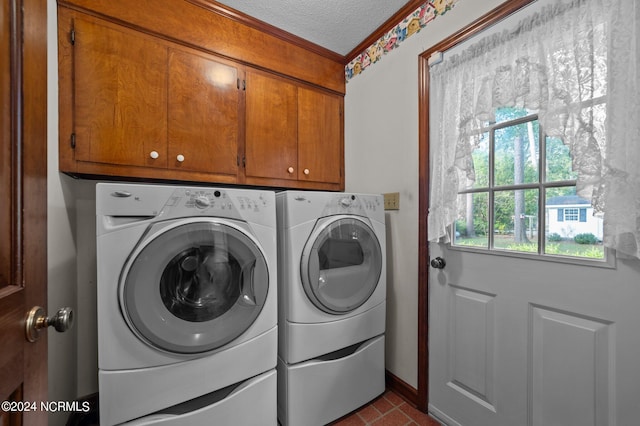 laundry area featuring washer and dryer, a textured ceiling, cabinets, and ornamental molding