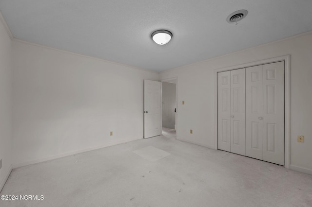 unfurnished bedroom with light carpet, crown molding, and a closet