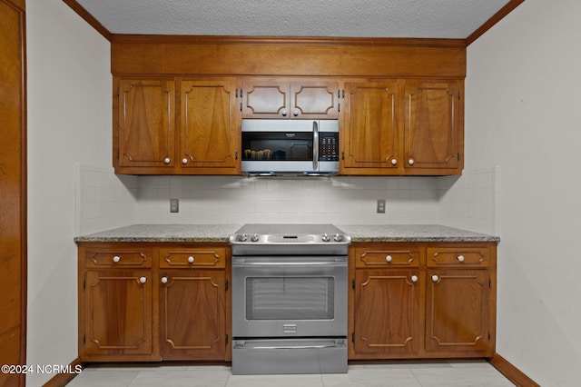 kitchen featuring appliances with stainless steel finishes, a textured ceiling, tasteful backsplash, and ornamental molding