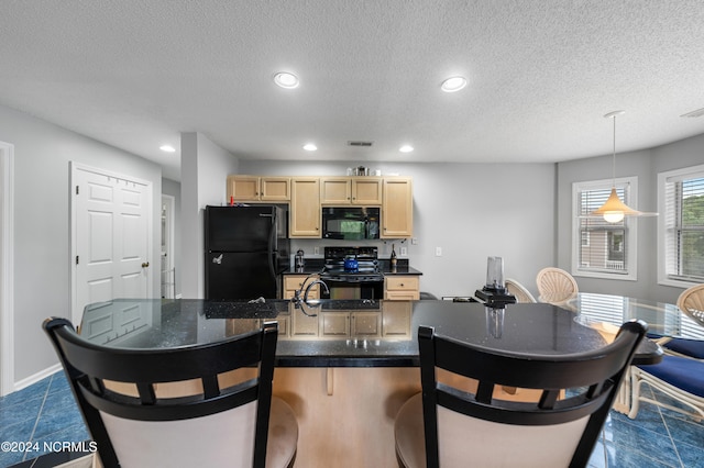 kitchen featuring dark tile patterned floors, light brown cabinets, black appliances, decorative light fixtures, and a textured ceiling