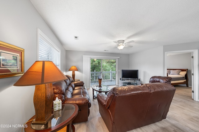 living room featuring light hardwood / wood-style flooring, a textured ceiling, and ceiling fan