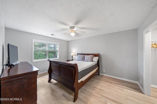 bedroom featuring a textured ceiling, light hardwood / wood-style floors, and ceiling fan