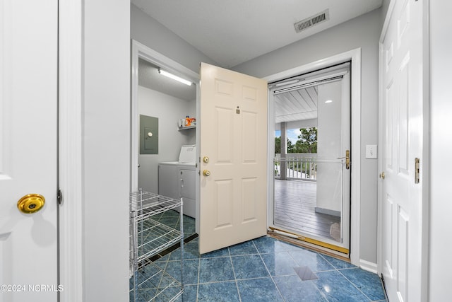 tiled entryway featuring electric panel, washing machine and clothes dryer, and a textured ceiling