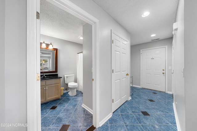 bathroom featuring vanity, toilet, a textured ceiling, and tile patterned flooring