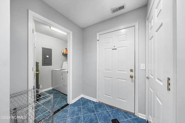 entrance foyer with washer and dryer, electric panel, a textured ceiling, and dark tile patterned flooring