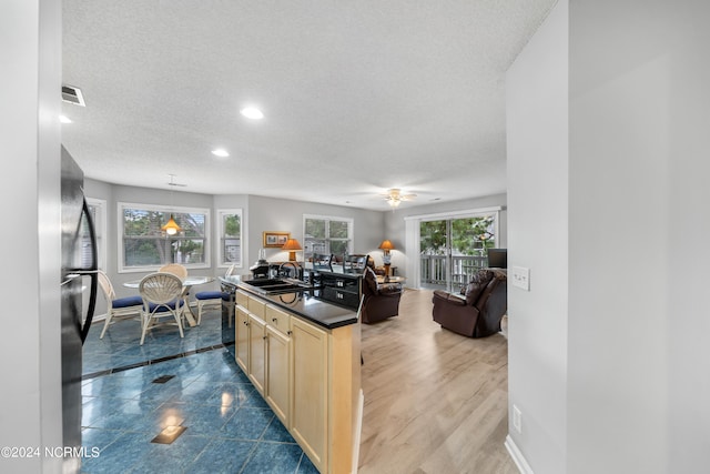 kitchen featuring ceiling fan, light brown cabinetry, a wealth of natural light, and decorative light fixtures