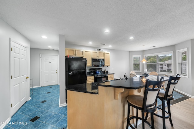 kitchen featuring black appliances, a textured ceiling, dark wood-type flooring, light brown cabinets, and a center island with sink