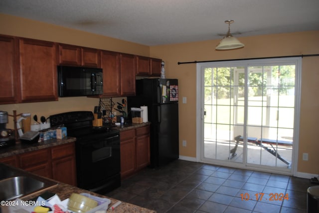 kitchen with dark tile patterned floors, black appliances, pendant lighting, and a textured ceiling