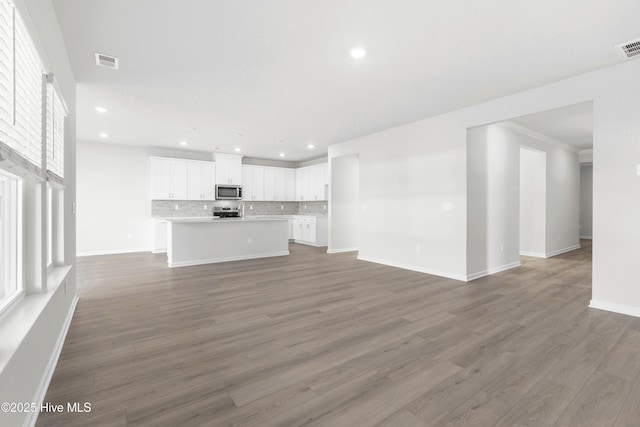 unfurnished living room featuring dark wood-type flooring and a healthy amount of sunlight