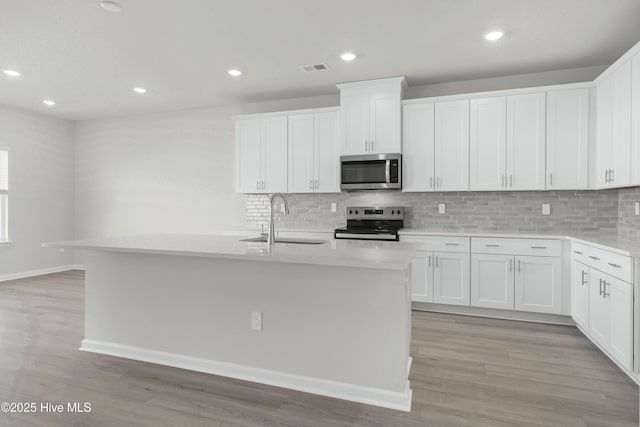 kitchen featuring white cabinets, stainless steel appliances, a center island with sink, and sink