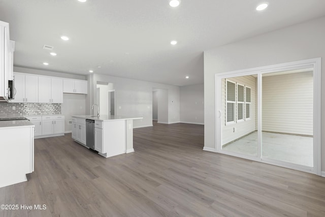 kitchen with a center island with sink, stainless steel dishwasher, tasteful backsplash, light hardwood / wood-style floors, and white cabinetry