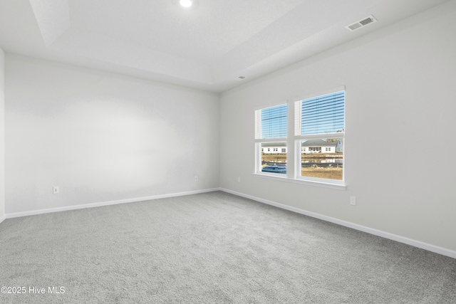 carpeted empty room with a tray ceiling