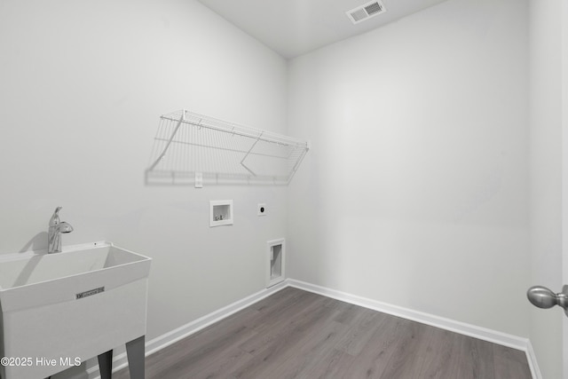 clothes washing area featuring hookup for a washing machine, dark hardwood / wood-style flooring, electric dryer hookup, and sink