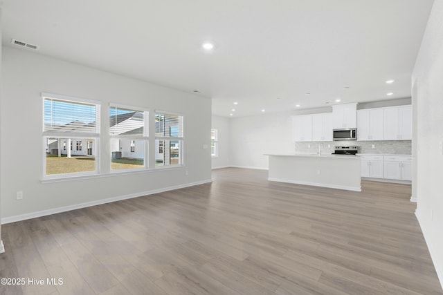 unfurnished living room with light hardwood / wood-style flooring and sink