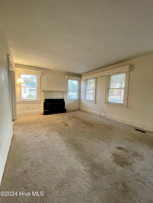 unfurnished living room featuring carpet and a healthy amount of sunlight