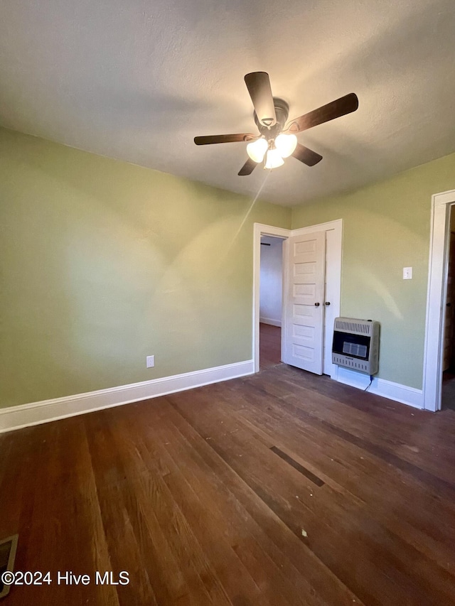 unfurnished living room with heating unit, ceiling fan, and dark wood-type flooring