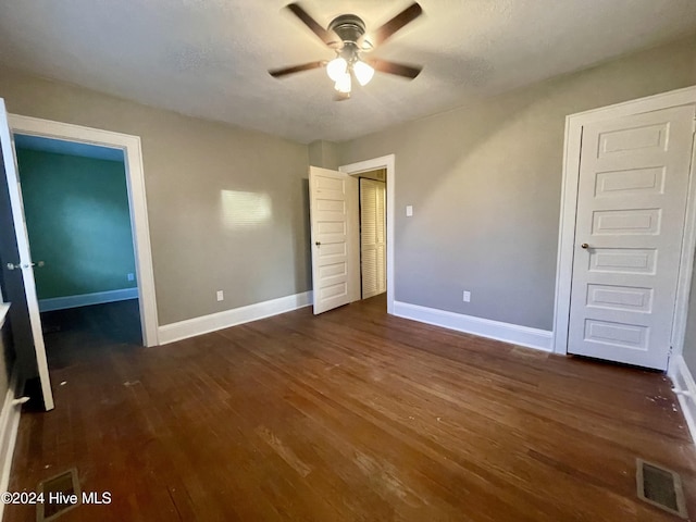 unfurnished bedroom featuring ceiling fan, dark wood-type flooring, and a textured ceiling