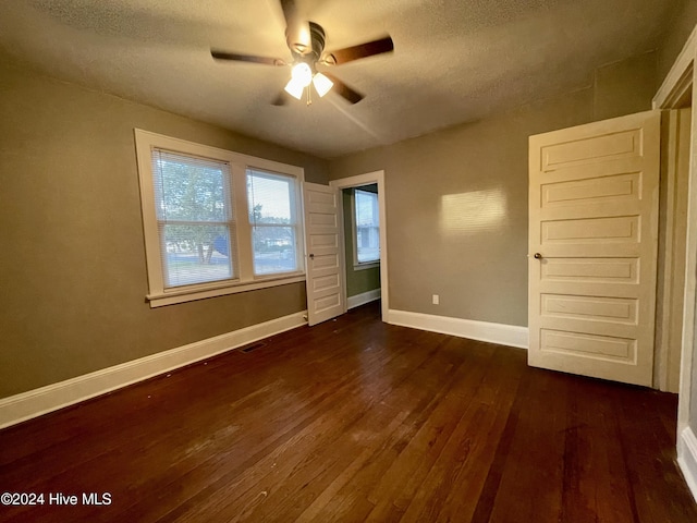 unfurnished bedroom with ceiling fan, dark wood-type flooring, and a textured ceiling