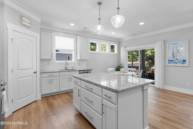 kitchen with sink, light wood-type flooring, a kitchen island, and white cabinets