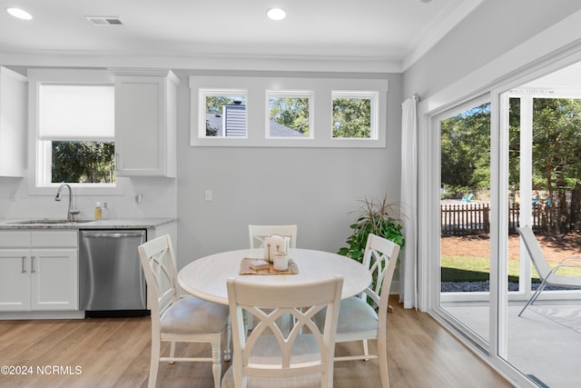 dining area with ornamental molding, sink, and light hardwood / wood-style flooring