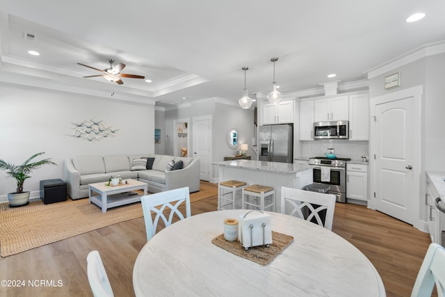 dining area featuring ornamental molding, light wood-type flooring, and ceiling fan