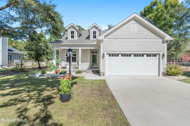 view of front of house featuring a porch, a front lawn, and a garage