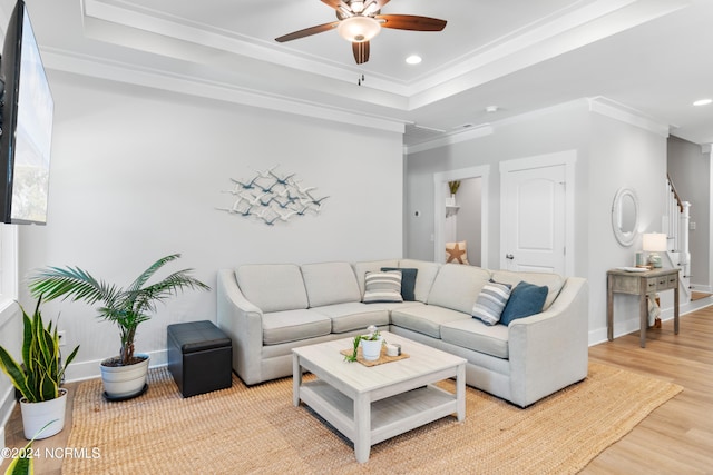 living room featuring light hardwood / wood-style floors, a raised ceiling, and crown molding