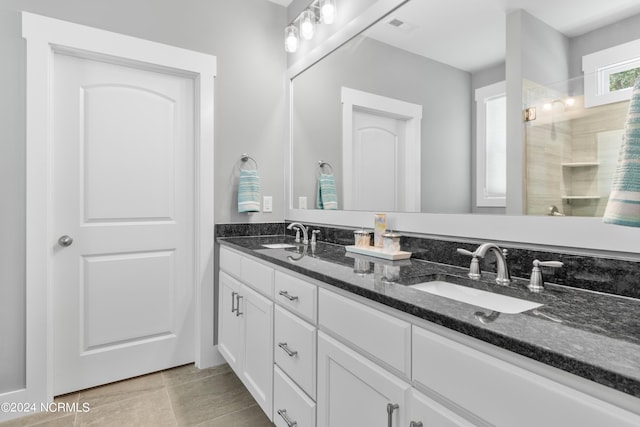 bathroom featuring vanity, a tile shower, and tile patterned floors