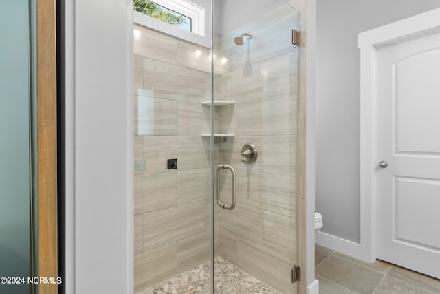 bathroom featuring toilet, tile patterned floors, and an enclosed shower