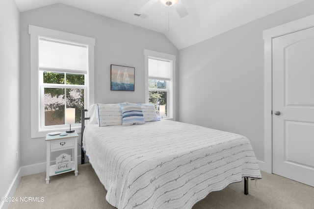 bedroom featuring ceiling fan, multiple windows, vaulted ceiling, and light colored carpet