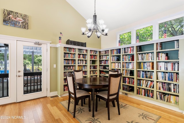 dining area featuring a notable chandelier, hardwood / wood-style flooring, high vaulted ceiling, and plenty of natural light